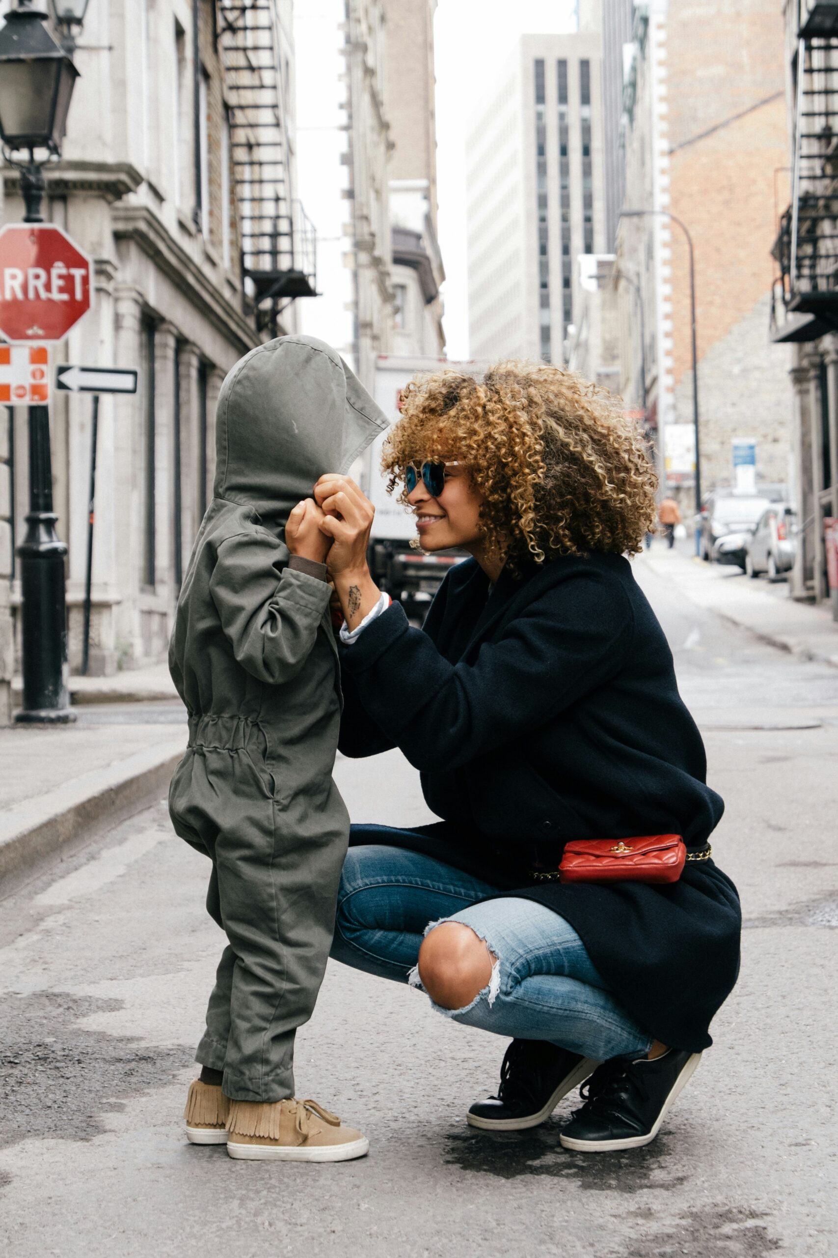 mother kneeling down and siling t child with hood on their head